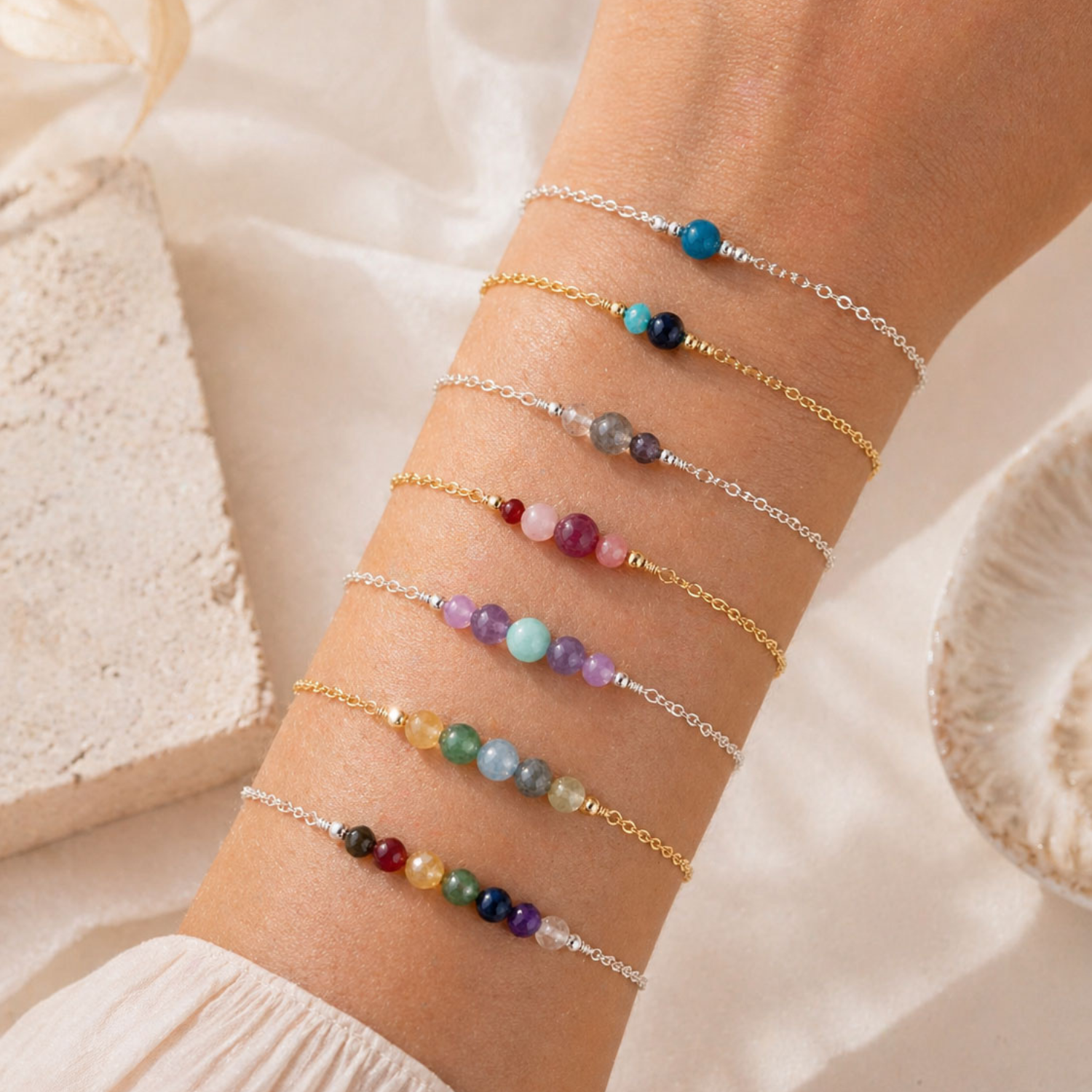 Multiple beaded bracelets on a wrist with a soft beige background